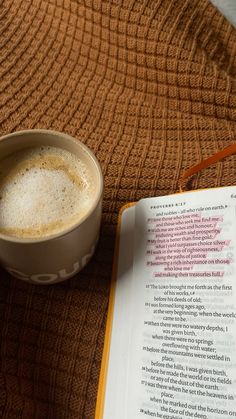 a cup of coffee next to an open book