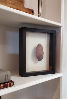 a framed piece of paper sitting on top of a white shelf