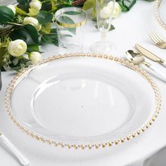 the table is set with white roses and gold cutlery, along with silverware