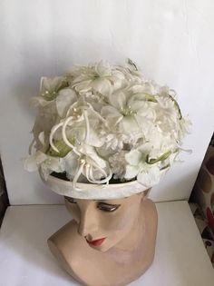 "Vintage 1960's hat. White floral with Green leaves bucket style hat. The label is *SEARS Fashion Millinery*. Sears Roebuck and Co. USA. *MORE INFORMATION BELOW* CONDITION: No issues noted. MEASURES: Inside circumference~21 1/2\" Height~5\" Front to back~8\" Left to right~7\" *WE APOLOGIZE~BUT WE NO LONGER SHIP TO GERMANY, ITALY OR SPAIN. IF ORDERS COME IN FROM GERMANY, ITALY OR SPAIN, WE WILL HAVE TO CANCEL THEM AND REFUND YOUR MONEY. SORRY FOR THIS INCONVENIENCE*" White Vintage Fascinator For Royal Ascot, White Vintage Cloche Fascinator, Vintage White Cloche Fascinator, Vintage White Fascinator Hat, White Vintage Fascinator Hat, Vintage White Headpiece For Kentucky Derby, Vintage White Mini Hat For Royal Ascot, White Vintage Top Hat With Curved Brim, Vintage White Fascinator With Curved Brim