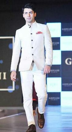 a man is walking down the runway in a white tuxedo suit and brown shoes