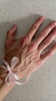 a person's hand with a white ribbon on it