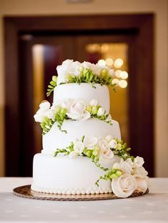 a three tiered white wedding cake with flowers on top