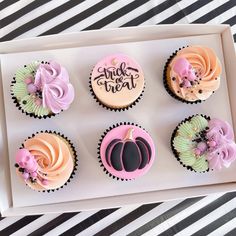 six decorated cupcakes in a box on a table