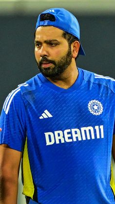 a man with a beard wearing a blue shirt and cap looking off to the side