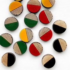 a bunch of different colored wooden buttons on a white surface with black, red, green and yellow stripes