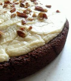 a chocolate cake with white frosting and nuts on top