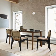 a dining room table with chairs and a vase on top of it next to a window