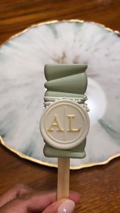 a hand holding a lollipop with the letters j and l on it in front of a mirror