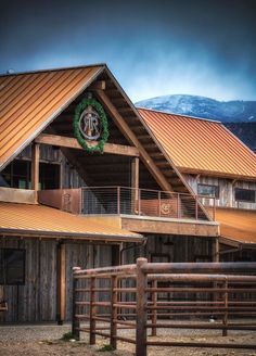 a large wooden building with a clock on it's face and a fence around it