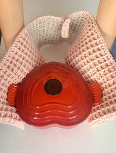 a red pot holder sitting on top of a white counter next to a person's legs