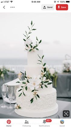 a white wedding cake sitting on top of a table next to a glass of wine