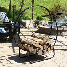 a fire pit sitting on top of a stone patio next to a pile of wood