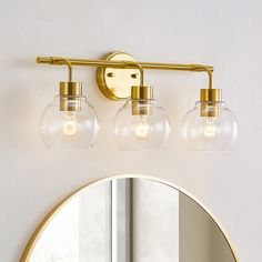 a bathroom light with three lights and a mirror on the wall next to it in front of a window