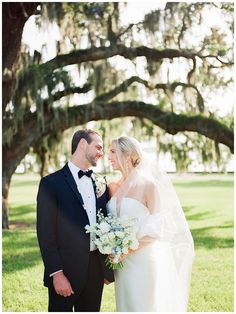 a bride and groom standing in front of an oak tree