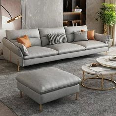 a living room with grey couches and orange pillows on the floor next to a coffee table