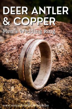 a wedding ring with antler and copper in it sitting on top of a rock