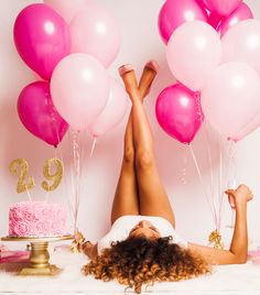 a woman laying on the floor with her legs up in front of pink and white balloons