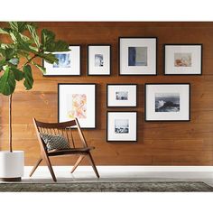 a wooden chair sitting in front of a wall filled with pictures and a potted plant