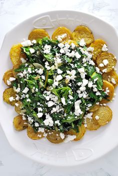 a white bowl filled with spinach and cheese on top of a marble countertop