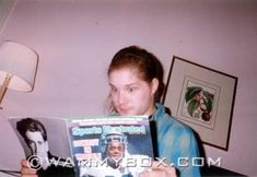 a woman holding up a magazine with an image of a football player on the cover