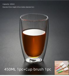 a glass filled with liquid and toothbrushes on top of a black countertop