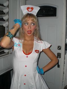 a woman in a nurse costume is holding her hair up to the side with one hand on her head