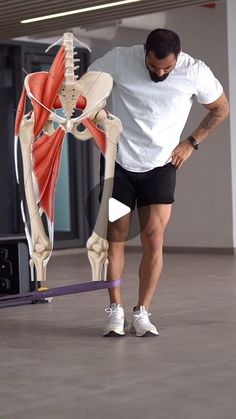 a man standing in front of a model of the human body and holding his leg