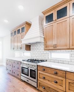 an empty kitchen with wooden cabinets and stainless steel stove top oven in the center island