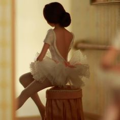 a doll sitting on top of a stool in front of a mirror with her legs crossed