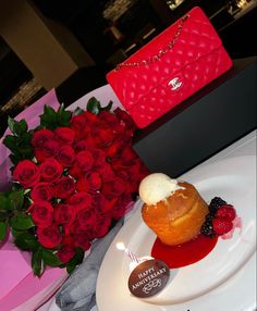 a table with roses, a heart shaped pastry and a red purse