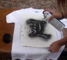 a person is painting a t - shirt with black ink on white paper and spray paint