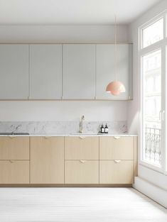 an empty kitchen with marble counter tops and wooden cabinetry, along with large windows