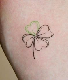 a small four leaf clover tattoo on the back of a woman's left thigh