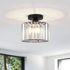 a ceiling light that is hanging from the ceiling in a room with white walls and windows