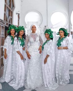 three women in white dresses and green head wraps standing next to each other with their hands on their hips