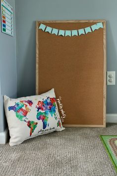 a bulletin board and pillow on the floor in front of a wall with a world map