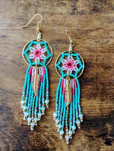 two pairs of earrings with beads on top of a wooden table