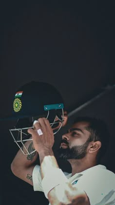 a man holding a cricket helmet up to his face