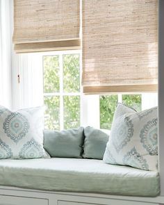 a white couch sitting next to a window in a living room with pillows on top of it