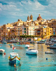 many boats are in the water near some buildings and blue sky with clouds above them