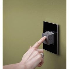 a person is pressing the switch button on a wall