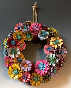 a wreath made out of paper flowers hanging on a wall