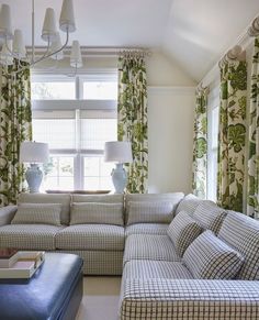 a living room with couches, lamps and curtains in front of a window that has green leaves on it