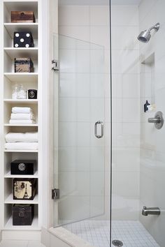 a walk in shower sitting next to a white shelf filled with towels