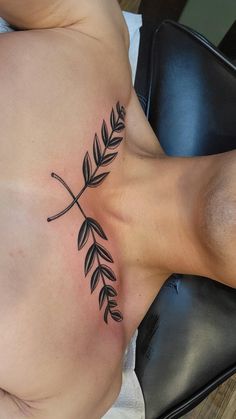 a woman with a tattoo on her stomach is laying in a chair and has an olive branch