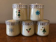 four jars with christmas decorations on them sitting on a table