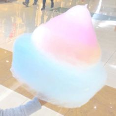 a person holding a large cotton candy in front of their face with blurry background