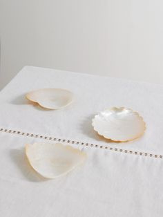 three seashells sitting on top of a white table