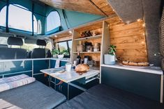 the interior of an rv with wood paneling and blue walls, windows, and shelves